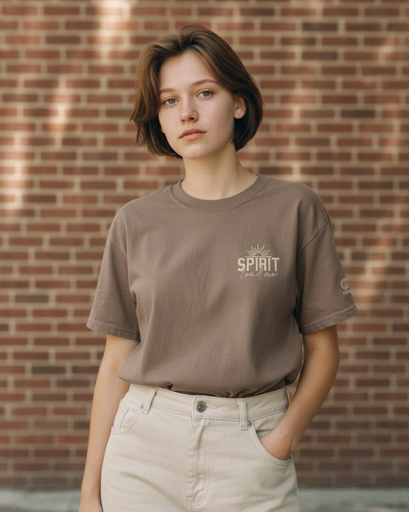 Person wearing a brown t-shirt with text against a brick wall