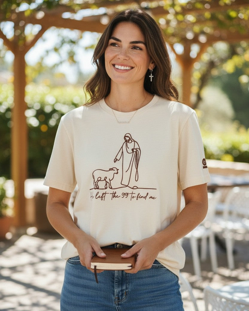 Woman wearing a white t-shirt with a graphic design, holding a book, standing outdoors.